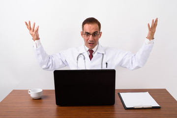 Mature Persian man doctor working behind desk