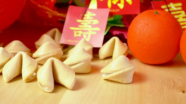 Chinese New Year party table in red and gold theme with food and traditional decorations. Macro close up dolly shot, focus on fortune cookies.