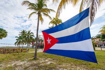 Cuban Flag Among Palm Trees. Beautiful tropical landscape on the background. Cuban flag against...