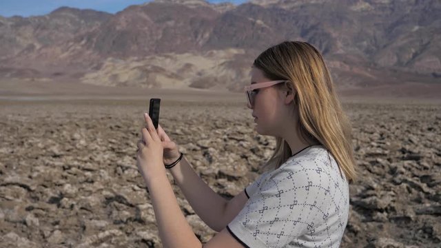 Millennial woman taking photos phone smart device on holidays Death Valley