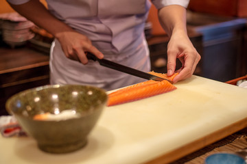 Japanese chef hand on cutting salmon prepare for making Donburi Salmon