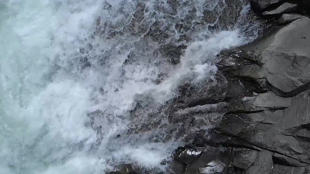 Powerful mountain river flowing over stones. Big black stones in mountain river.