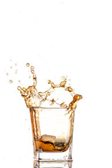 big splash from falling ice in a glass of whiskey on a white background