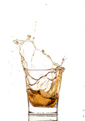 big splash from falling ice in a glass of whiskey on a white background