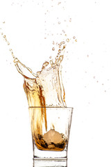 big splash from falling ice in a glass of whiskey on a white background