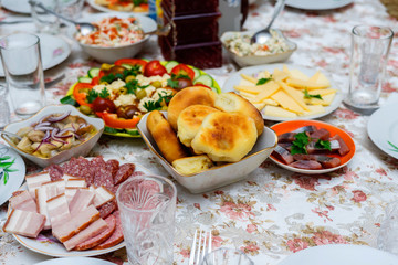 home feast. on the table is a cup with pies, sausage sliced ​​plate, mixed vegetables, cheese, herring