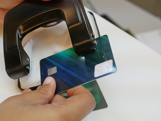 A credit card in a woman's hands being cut / punched by a hole puncher - breaking free of financial bondage