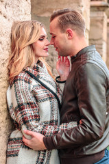 happy romantic couple in love kisses outdoors near the old building on a cold autumn day, concept of mutual love relations