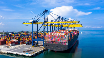 Container ship at industrial port loading and unloading containers in import export business logistic and transportation of international by container ship in the open sea. - obrazy, fototapety, plakaty