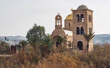 Fototapeta na wymiar ancient and modern stone churches at the site of the baptism of jesus on the jordan river viewed from the west bank