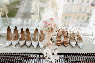 Woman Round-toe Pumps Shoes Collection and Roses Flowers Bouquet Standing on Windowsill. Bridal Floral Accessory Decorated Ribbons, Spool Heels and Pointed Toe T-strap. City Street on Background