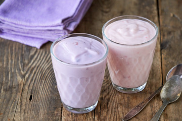 Two glasses of fruit yogurt on a wooden table