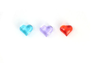 Blue, red and lilac glass hearts  on white background. Stock photo for Valentine's Day with empty place for text. For web, print, cards, invitations, wallpaper.