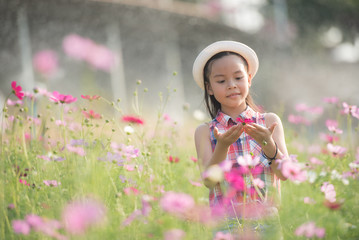 traveler or tourism. happy little asian girl child in cosmos flower fields  with big smile and laughing healthy happy funny smiling face young adorable lovely female kid.  happy lifestyle concept.