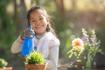 adorable 8 years old asian little girl is watering plant in pots in garden outside house, child education of nature. caring for a new life. earth day holiday concept. world environment day. ecology.