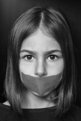 Unhappy girl with sticky tape over her mouth. Violation of human rights. Kidnapping.