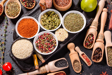 Spices and herbs over black stone background. Top view with free space for menu or recipes
