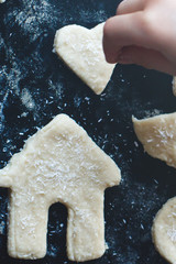 A child sprinkles cookies with coconut before baking. Top view