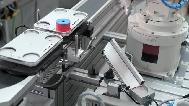 Close-up of robot arm pick product from automated car and place to station to be assembly. Industry 4.0 smart factory concept; robot arm assembles the product. Selective focus.