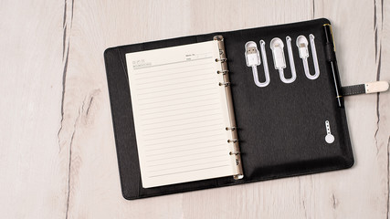 Opened leather notebook with built in power bank on wooden background. Diary with built in power...