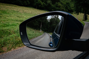 The car on the road with the forest around it.