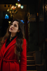 Beautiful young woman in a red coat goes outside