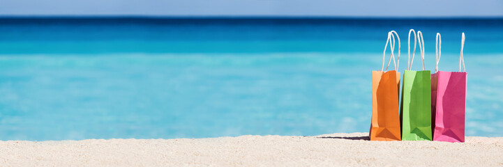 Shopping bags on sand against turquoise caribbean sea water