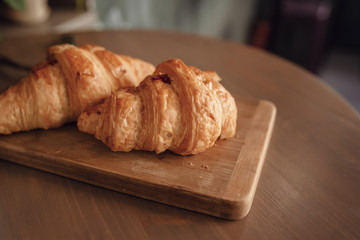 Cappuccino with beautiful latte art and croissant on wooden background