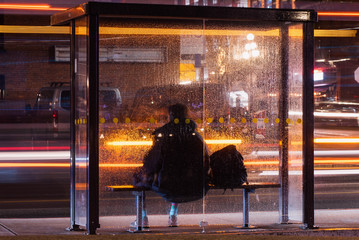 passing buss and a man sitting in a bus stop 