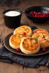 Cottage cheese pancakes Russian syrniki with red currant and yogurt, selective focus.