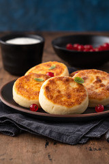 Cottage cheese pancakes Russian syrniki with red currant and yogurt, selective focus.
