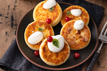 Cottage cheese pancakes Russian syrniki with red currant and yogurt, selective focus.