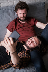 Fototapeta premium Two men taking selfie on the sofa
