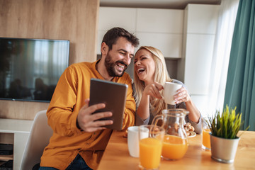 Obraz na płótnie Canvas Cheerful couple having breakfast at home