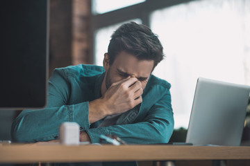 Unhappy cheerless man touching the bridge of the nose