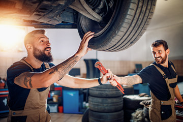 Two mechanics repairing car in service center