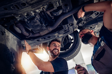 Fototapeta na wymiar Two mechanics repairing car in service center