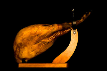Whole iberian ham on a black baclground