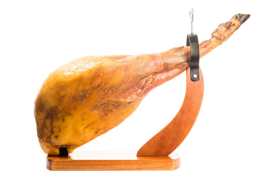 Whole Iberian ham leg in a wooden ham stand isolated