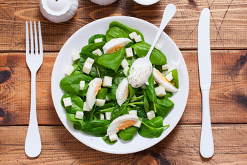 Step-by-step preparation of spinach salad with egg and cheese, step 5 - adding sauce to the salad, top view, selective focus