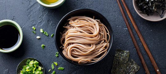 Soba noodles with sauce and garnishes. Japanese food. Top view. Black slate background. - obrazy, fototapety, plakaty