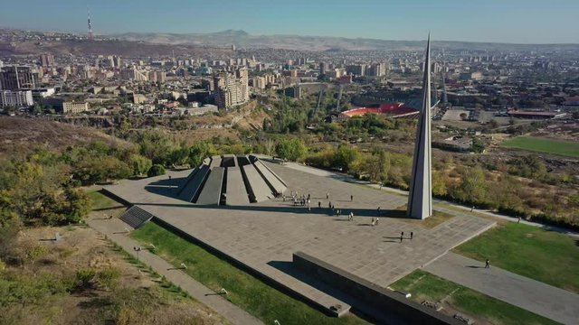 Aerial drone zoom out shot of Tsitsernakaberd museum on background of city panorama in summer in Yerevan, Armenia. Drone shot of Yerevan museum with city panorama view