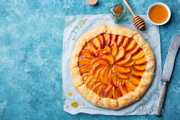 Peach galette, pie, cake with cream on blue background. Top view. Copy space. - obrazy, fototapety, plakaty