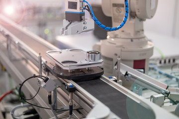 Focus on robot arm's gripper. Industry 4.0 concept; artificial intelligence in smart factory. Robot picks up the product from automated car on the manufacturing line. Selective focus.