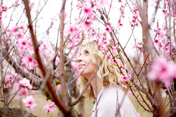 portrait of beautiful pregnant woman posing against the pink flower trees gardenand fog in spring,...