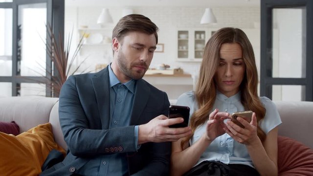 Business couple surfing internet on smartphones. Man showing news on mobile