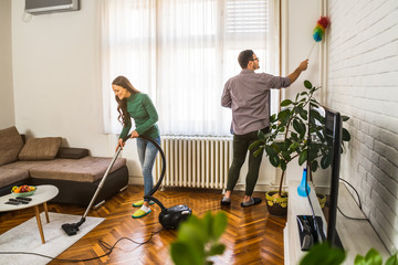 Young happy couple is cleaning their apartment. - obrazy, fototapety, plakaty