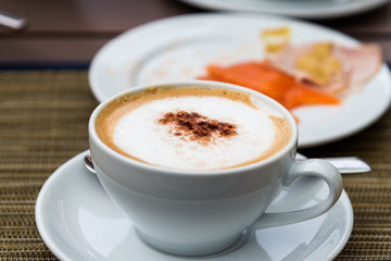 cup of coffee with cream on wooden background
