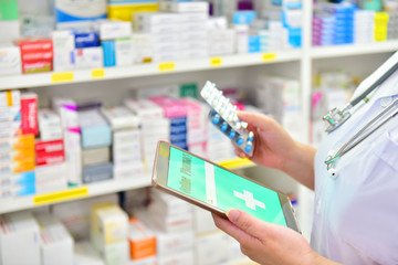Doctor holding medicine capsule pack and computer tablet for filling prescription in pharmacy...
