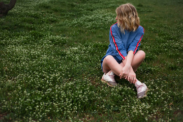 Fototapeta premium Unity with the nature of the woman, female sit on spring green grass in peach flower garden. It healthy to breath healthy air The model wearing denim dress .